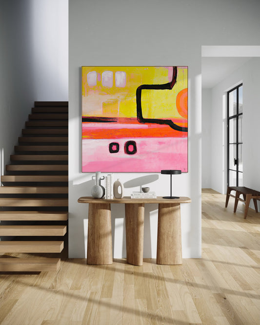 IN TRANSIT 'ARRIVAL' fine art print by Australian artist Ash Badios, featuring vibrant yellow, orange and pink painterly layers with bold black curved lines and geometric markings, displayed above a sculptural timber console beside a floating staircase in a contemporary entryway.